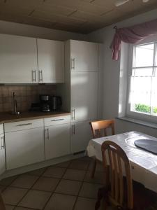 a kitchen with white cabinets and a table and a window at Ferienwohnung Nett in Adenau