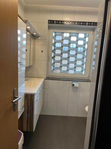 a white bathroom with a sink and a window at Marina, Ferienwohnung in Schneverdingen