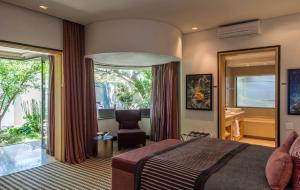 1 dormitorio con 1 cama, 1 silla y 1 ventana en Mantis No5 Boutique Art Hotel en Port Elizabeth