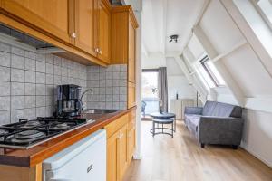 a kitchen with a stove top oven next to a living room at Appartementen Beatrix in De Koog