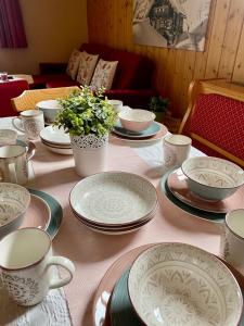 a table with plates and cups and flowers on it at Landhaus Birgbichler - Apartments mit Bergblick inklusive Sommercard in Ramsau am Dachstein