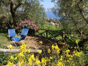 two blue chairs sitting in a garden with flowers at Antico Casale Ruoppo in SantʼAgata sui Due Golfi