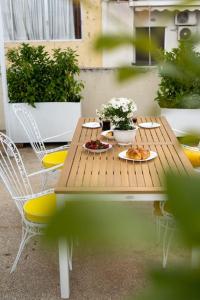 une table et des chaises en bois avec de la nourriture et des fleurs. dans l'établissement Ebullience - Stylish & Chic Athens Apartment, à Athènes