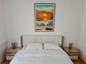 a bed in a bedroom with a painting on the wall at Art Apartment in Podgorica