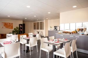 comedor con mesas y sillas blancas y cocina en Séjours & Affaires Paris Vincennes en Vincennes