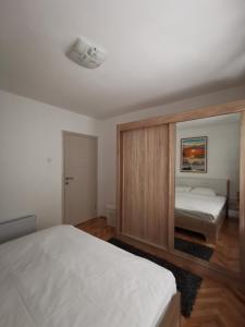 a bedroom with two beds and a large mirror at Art Apartment in Podgorica