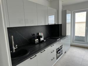 布加勒斯特的住宿－Fabulous Penthouse Lakeview W20，厨房配有白色橱柜和黑色台面