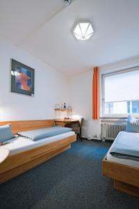 1 Schlafzimmer mit 2 Betten, einem Schreibtisch und einem Fenster in der Unterkunft Hotel der Akademie C. Pirckheimer Haus in Nürnberg