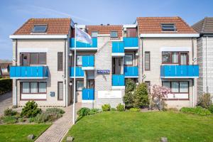 un edificio de apartamentos con balcones azules y un patio en Appartementen Beatrix, en De Koog