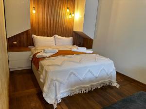 una camera da letto con un grande letto con coperte e cuscini bianchi di Апартамент НИА a Velingrad