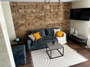 un soggiorno con divano blu e muro di mattoni di Апартамент НИА a Velingrad