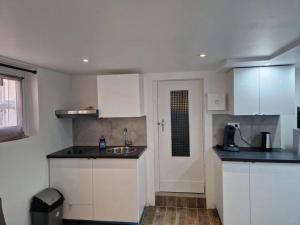 a kitchen with white cabinets and a sink at Studio paisible CDG/Villepinte/Le Bourget in Aulnay-sous-Bois