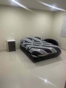 a bed in a white room with a black comforter at Hermosa Casa Minimalista cerca a la Naturaleza in Cochabamba