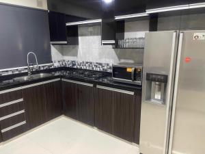 a kitchen with wooden cabinets and a stainless steel refrigerator at Hermosa Casa Minimalista cerca a la Naturaleza in Cochabamba