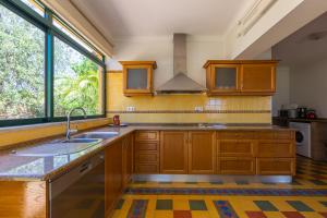 een keuken met houten kasten, een wastafel en een raam bij Vila Limão in Boliqueime