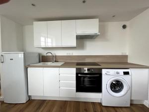 a kitchen with white cabinets and a washer and dryer at Superbe duplex plein centre in Lamballe Armor