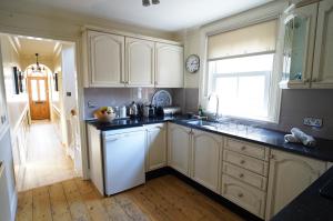 a kitchen with white cabinets and a white dishwasher at Nutcroft, Cowes in Cowes