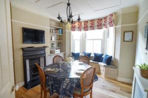 a dining room with a table and chairs and a fireplace at Nutcroft, Cowes in Cowes