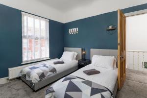 two beds in a room with blue walls at Crawford Avenue Retreat in Liverpool