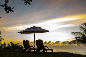 two chairs and an umbrella in front of the ocean at Sungazer in Arraial d'Ajuda