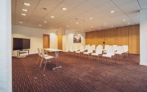 uma sala de conferências com cadeiras brancas e uma televisão em Hotel Strela by Mountain Hotels em Davos
