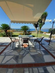 une terrasse avec une table et des chaises sous un grand parasol dans l'établissement Mediterranean Studios, à Lassi