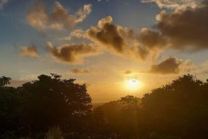a sunset in the sky with trees in the foreground at Le Ptit Gibs in Petit-Bourg