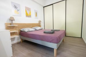 - une chambre avec un grand lit et des draps violets dans l'établissement La Petite Escale, à Avignon