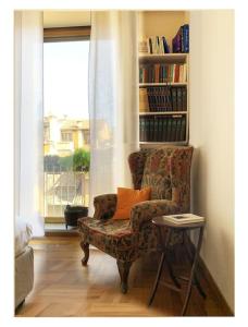 uma sala de estar com uma cadeira e uma estante de livros em Elegant Apartment San Babila ,5 minutes from Duomo em Milão