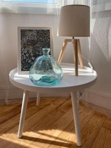 un tavolo con un vaso di vetro e una lampada sopra di Chez Mathilde-appartement 2-Calais Nord /Citadelle a Calais