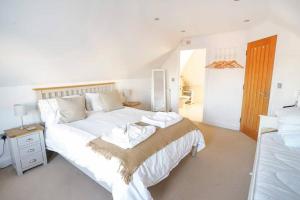 a bedroom with a large white bed with towels on it at The Pilot House - Cowes in Cowes