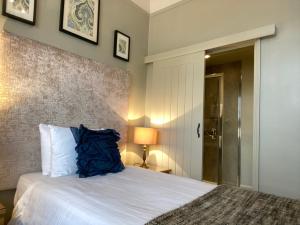 a bedroom with a bed with a blue pillow on it at Virginia Court Hotel in Cromer