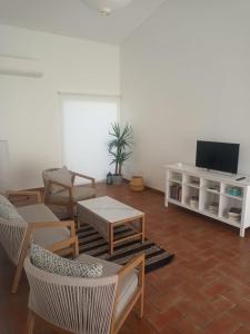 uma sala de estar com uma televisão e uma mesa e cadeiras em Monte Papa Figos em Malhão