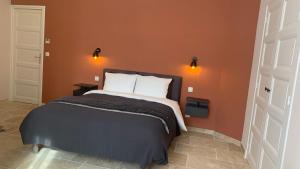 a bedroom with a bed with an orange wall at Logis de la Foulerie in Bize-Minervois