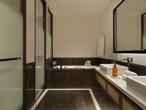 a bathroom with two sinks and a glass shower at City of Dreams Mediterranean - Integrated Resort, Casino & Entertainment in Limassol