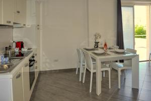uma cozinha branca com uma mesa e cadeiras brancas em MARIMAR - Apartments OTRANTO em Otranto