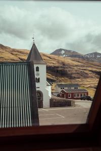 a church with a clock tower in a parking lot at 3-Bedroom Home in Eiði 
