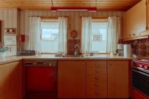 a kitchen with a sink and a stove and windows at 3-Bedroom Home in Eiði 