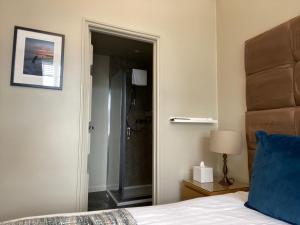 Schlafzimmer mit einer Tür, die zu einer Dusche führt in der Unterkunft Virginia Court Hotel in Cromer