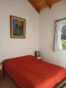 a bedroom with a red bed and a window at Hostel Otto Tipp in El Bolsón