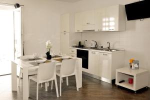 MARIMAR - Apartments OTRANTO في أوترانتو: مطبخ أبيض مع طاولة وكراسي وكاونتر