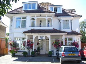 a white house with a car parked in front of it at Alexander Lodge in Bournemouth