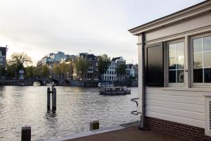 een gebouw naast een rivier met een boot erin bij SWEETS Walter Süskindbrug in Amsterdam