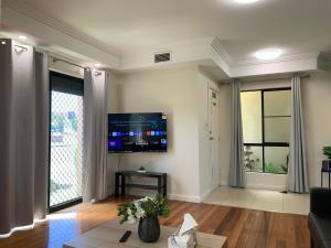 sala de estar con sofá y TV en la pared en Comfy place with all en Revesby