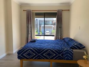 a bed with a blue comforter and a window at Comfy place with all in Revesby