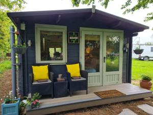 a tiny house with yellow pillows on the porch at Mulberry Cottage Farm in Wyboston