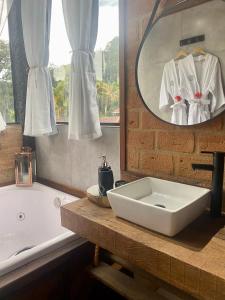 a bathroom with a sink and a tub and a mirror at Pousada do Figa in Visconde De Maua