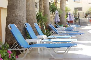 a row of blue chairs and umbrellas on a patio at Diogenis Blue Palace in Gouves