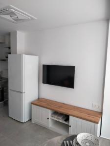 a kitchen with a white refrigerator and a flat screen tv at MARiPEP Playa Vinaròs in Vinaròs