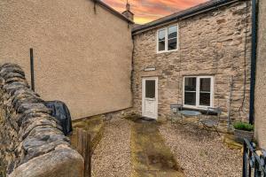 a stone house with a stone wall and a white door at Finest Retreats - Westcote Cottage in Bradwell